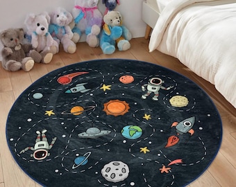 Puede incluir: Una alfombra redonda de color azul y negro con temática espacial con una variedad de planetas, estrellas, cohetes y astronautas. La alfombra es perfecta para una habitación infantil o un área de juegos.