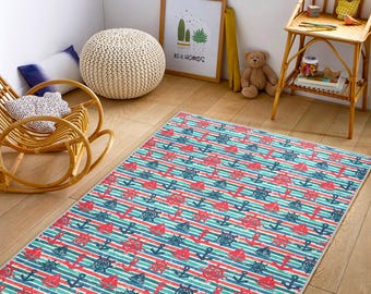 May include: A rectangular nautical-themed rug with a pattern of red anchors, blue ship wheels, and red and blue striped lines. The rug is placed on a wooden floor, with a rocking chair and a small side table in the background.