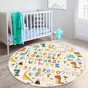 May include: A round, cream-colored play mat with a colorful dinosaur theme. The mat features the alphabet, numbers 1-9, and a variety of dinosaurs in shades of green, blue, orange, and yellow. The mat is perfect for a child's playroom or nursery.