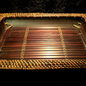 Puede incluir: Una bandeja rectangular tejida con una base de bambú marrón y un borde de mimbre marrón oscuro.