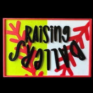 May include: A rectangular sign with the words "Raising Balls" in black, stylized lettering. The background is split into yellow and white sections, with red arrow-like shapes and a red border.