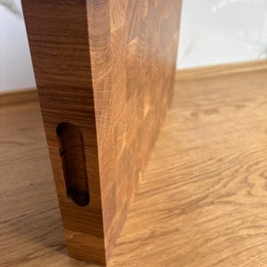 Puede incluir: Tabla de cortar rectangular de madera marr&oacute;n claro con veta visible. Tiene un asa integrada en un lado. Esta tabla de cortar est&aacute; dise&ntilde;ada para uso en la cocina y est&aacute; hecha de madera maciza.