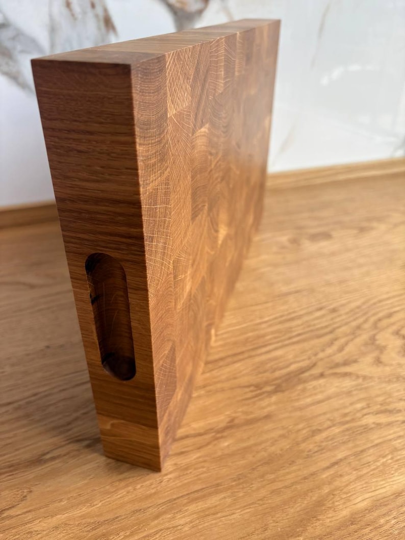 Puede incluir: Tabla de cortar rectangular de madera marr&oacute;n claro con veta visible. Tiene un asa integrada en un lado. Esta tabla de cortar est&aacute; dise&ntilde;ada para uso en la cocina y est&aacute; hecha de madera maciza.