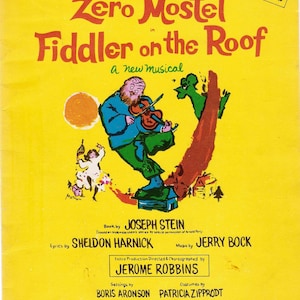 Może przedstawiać: Żółta okładka nut z ilustracją kreskówkową mężczyzny grającego na skrzypcach. Tytuł to "Zero Mostel w Skrzypku na dachu, nowy musical".