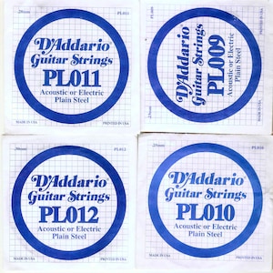 May include: Four D'Addario guitar string packages with blue and white labels. The labels have the D'Addario logo, the text "Guitar Strings", and the product number, which is PL011, PL009, PL012, and PL010. Each package also says "Acoustic or Electric Plain Steel".
