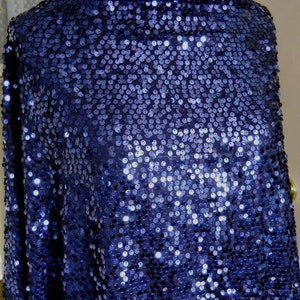 Peut inclure: Un gros plan sur un tissu bleu marine recouvert de paillettes. Les paillettes sont petites et rondes, et elles créent un effet chatoyant.