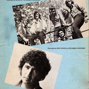 Peut inclure: Une pochette d'album vintage avec une photo en noir et blanc d'un groupe de musiciens. La pochette de l'album est bleue et blanche avec le titre "I BELIEVE IN MUSIC" et les mots "Words and Music by MAC DAVIS" et "Recorded by GALLERY on SUSSEX RECORDS".