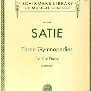 Pode incluir: Capa de partitura para "Three Gymnopedies" de Satie, publicada pela Schirmer's Library of Musical Classics. A capa creme apresenta texto verde e bordas decorativas. O título "SATIE" é exibido em destaque.
