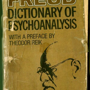Może przedstawiać: Okładka starej książki z brązowym tłem i tytułem "FREUD DICTIONARY OF PSYCHOANALYSIS" w czarnym kolorze. Książka zawiera przedmowę autorstwa Theodora Reika i przedstawia czarno-białą ilustrację mężczyzny w okularach.