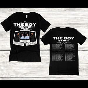 May include: Black t-shirts with white text and graphics. One shirt features "THE BOY IS MINE TOUR" with Brandy and Monica's names and photos. The other shirt has the tour dates. A music-themed apparel item.