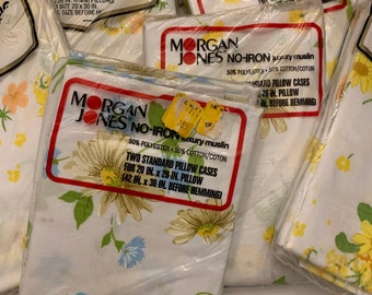May include: Four packages of Morgan Jones No-Iron luxury muslin pillowcases. The packages are white with a floral pattern and feature the brand name and product details. The pillowcases are 50% polyester and 50% cotton.