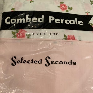 May include: A white sheet with a pink floral pattern, packaged in plastic. The packaging has black text that reads "Combed Percale Type 180" and "Selected Seconds". The bottom of the packaging has black text that reads "6 Cotton RN 13720 Made in U.S.A."