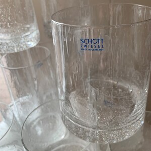 May include: A stack of clear glass tumblers with a textured surface. The tumblers are made by Schott Zwiesel and say "Made in Germany" on the bottom.