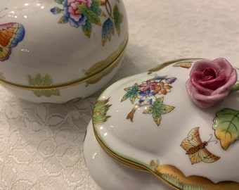 May include: Two porcelain trinket boxes with floral and butterfly designs. The boxes are decorated with 3D flowers and butterflies. The boxes are white with gold trim.