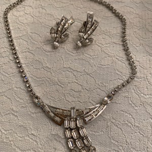 May include: A silver necklace and earrings set with a crystal teardrop pendant and matching crystal earrings.