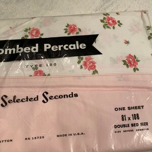 May include: A pink and white floral patterned sheet in a plastic bag. The bag has the text "Combed Percale Type 180" and "Selected Seconds". The sheet is labeled as "One Sheet 81 x 108 Double Bed Size Size Before Hemming".