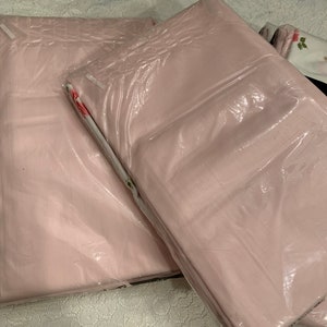 May include: A set of three pink pillowcases packaged in plastic. The pillowcases have a floral pattern.