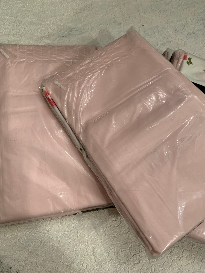 May include: A set of three pink pillowcases packaged in plastic. The pillowcases have a floral pattern.
