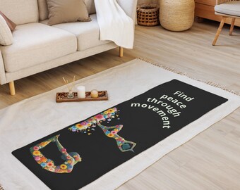 Puede incluir: Estera de yoga negra con un diseño floral de dos personas en poses de yoga. El texto "Find peace through movement" está impreso en la estera.