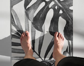 May include: Black and white bath mat with a tropical leaf design. The mat is shown with bare feet standing on it.