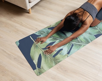 Könnte beinhalten: Eine Person, die eine Yoga-Pose auf einer blauen Yogamatte mit grünem tropischem Blatt-Muster macht.