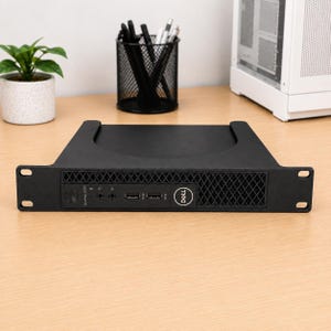 Può includere: Un computer Dell OptiPlex 3000 nero montato in un telaio rack. Il pannello frontale presenta un pulsante di accensione, due jack audio, due porte USB e una griglia di ventilazione. Il logo Dell è visibile sul lato destro del pannello.