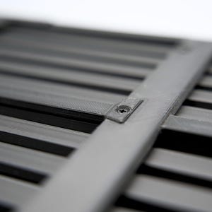 May include: Close-up of a gray, slatted object with a crossbar secured by a screw. The object has a series of parallel, dark gray slats. The crossbar is a lighter shade of gray.