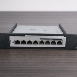 Könnte beinhalten: Ein schwarzer Netzwerk-Switch mit mehreren Ports, nummeriert und mit der Aufschrift "PoE OUT". Das Gerät ist in einem Rack montiert, mit dem Markennamen "Ubiquiti" auf der Oberseite. Der Switch ist für die Netzwerkkonnektivität konzipiert.