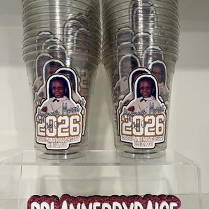 May include: Two clear plastic cups stacked in columns, each featuring a custom decal of a person, the name Ayanna Morris, the year 2026, and Loyola University Chicago. Below, a pink glitter sign displays the text PPLANNEDBYPAIGE with social icons.