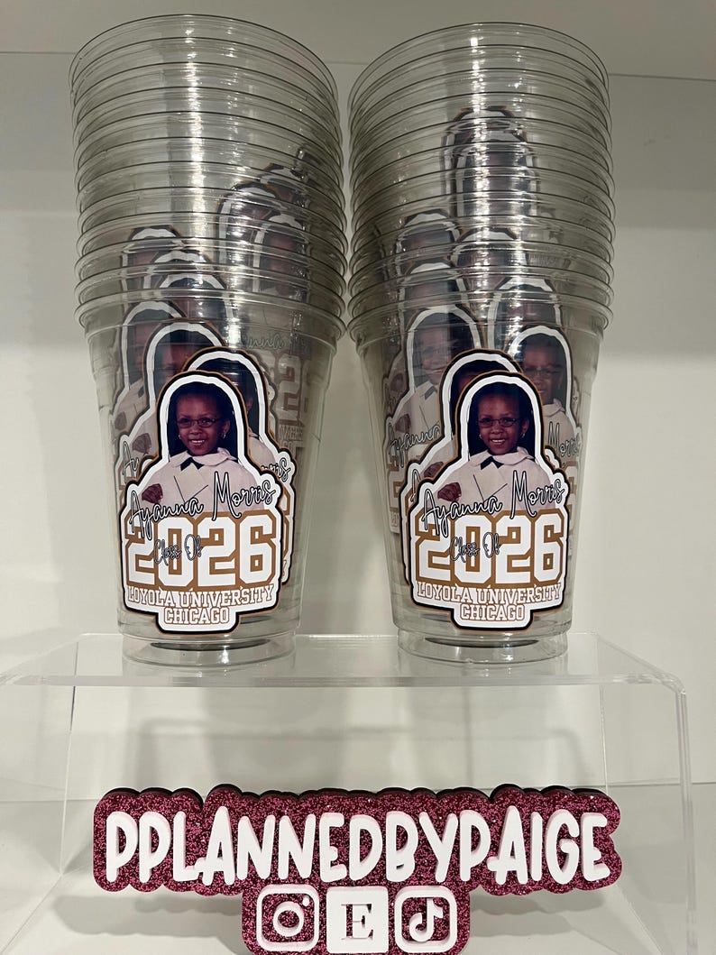 May include: Two clear plastic cups stacked in columns, each featuring a custom decal of a person, the name Ayanna Morris, the year 2026, and Loyola University Chicago. Below, a pink glitter sign displays the text PPLANNEDBYPAIGE with social icons.