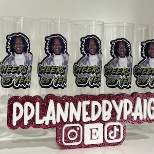 Pu&ograve; includere: Cinque bicchieri alti trasparenti con la grafica di una persona dai capelli scuri e il testo Cheers to 25 Years. Davanti, un'insegna glitterata rosa scuro mostra il testo PPLANNEDBYPAIGE con icone dei social media Instagram, Etsy e TikTok.