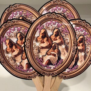 May include: A collection of oval-shaped hand fans. Each fan features a portrait of a person in a gold frame with the text "The Art of 30" in pink script. The fans have wooden handles.