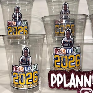 May include: Clear plastic cups featuring a graphic of a child holding a sign that reads pre-K, with colorful alphabet blocks, the text Denver Class of 2026, and the word CONGRATULATIONS in yellow and blue. A maroon glitter sign reads PPLANNER.