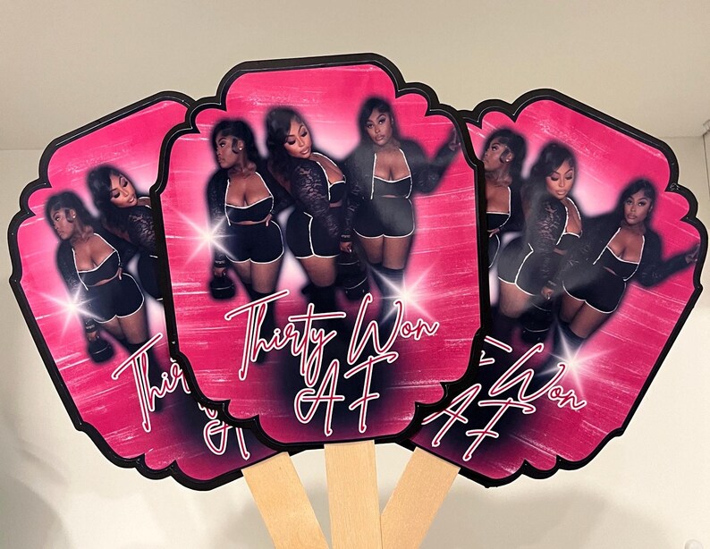 May include: Three decorative hand fans with a pink background and a black border. Each fan features a photo of women in black outfits. The text "Thirty Won AF" is written in white script on each fan.