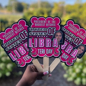 May include: Three pink and black Libra-themed fan decorations with the text "President of the Baddest Bitches" and "United States of Libra." Each fan features a portrait of a woman and the words "Teri Day."
