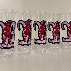 Pu&ograve; includere: Cinque bicchieri alti trasparenti con una stampa grafica di una persona in un completo rosso e un design a corna di ariete rosa. Il testo "Aries Baddie" e "Bad Bitch Holiday" &egrave; stampato in lettere rosa e bianche su ogni bicchiere.