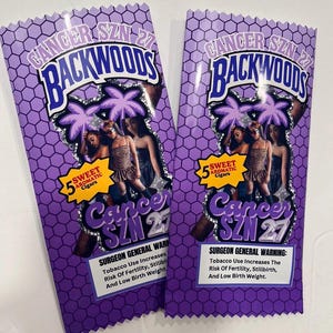 May include: Two purple Backwoods cigar packs. The packs feature the text "CANCER SZN 27" and "BACKWOODS" in a stylized font. The packs also include an image of women and the text "5 SWEET AROMATIC Cigars". A Surgeon General warning is also present.
