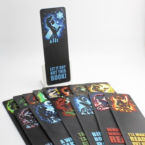 May include: A collection of black bookmarks with colourful character illustrations. One bookmark displays a silhouette and the text "LET IT GO? NOT THIS BOOK!". Other bookmarks feature various designs and text.
