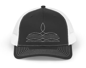 May include: A black and white trucker hat with a white mesh back. The front of the hat features a white embroidered design of a stylized geometric shape.