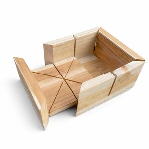 May include: A wooden miter box with a natural finish. The box has a rectangular shape with angled sides and a series of saw guides. The sliding section has multiple angled slots for precise cuts. Ideal for woodworking projects.