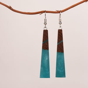 May include: A pair of long, teal blue and brown resin earrings with silver hooks.