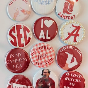 May include: A collection of twelve circular pin-back buttons featuring various Alabama Crimson Tide themes. Designs include text like 'To The Tide', 'Roll Tide', 'Alabama Gameday', 'SEC', 'I Heart AL', 'In My Gameday Era', and 'If Lost Return To Bryant Denny'.