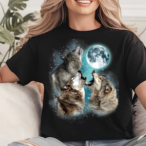 May include: A black t-shirt with a graphic of three wolves howling at the moon. The wolves are silhouetted against a blue sky with stars. The moon is full and white.