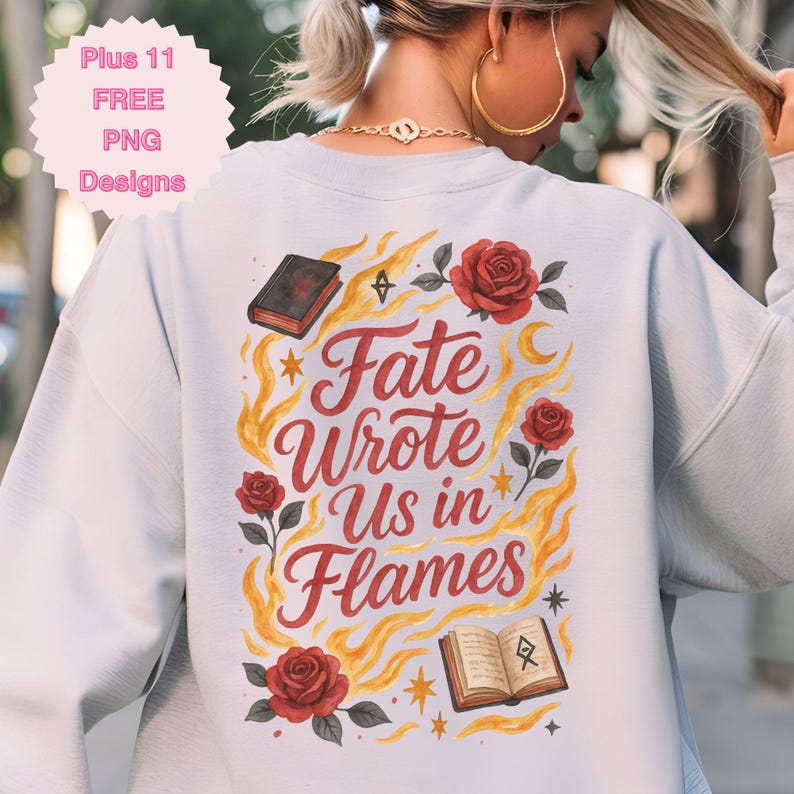 May include: A light blue sweatshirt with the text "Fate Wrote Us in Flames" in red script, surrounded by illustrations of roses, books, flames, and stars. The design is centered on the back of the sweatshirt.