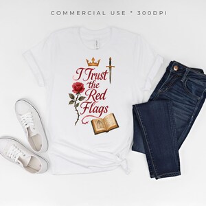 May include: White t-shirt with the text "I Trust the Red Flags" in a decorative font, along with a rose, crown, sword, and open book graphic. Dark blue jeans and white sneakers are also in the image.