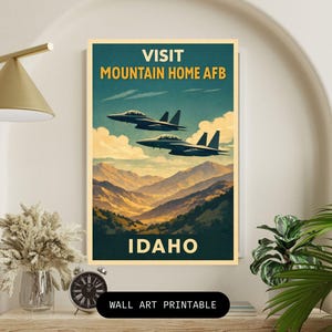 Pode incluir: Um cartaz de viagem em estilo vintage para Mountain Home AFB em Idaho. O cartaz apresenta dois jatos de combate voando sobre uma cordilheira. O texto "VISIT MOUNTAIN HOME AFB" e "IDAHO" é exibido em negrito, com fontes vintage.