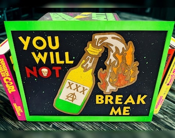 May include: A wooden sign with a black background and a green frame. The sign features the words "YOU WILL NOT BREAK ME" in yellow and green, with a skull and a bottle graphic. The bottle is yellow with a white label and the letters "XXX".
