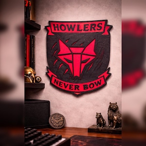 May include: A wooden wall plaque with a red and black wolf design. The plaque reads "HOWLERS" at the top and "NEVER BOW" at the bottom. The wolf head is in the center. The plaque is mounted on a gray wall.