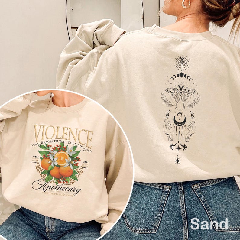 May include: Sand-colored sweatshirt with a graphic on the front that reads "VIOLENCE BASGIATH WAR COLLEGE Apothecary". The back of the sweatshirt features a black celestial design with a moth and hands. The sweatshirt is made of a soft material.