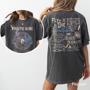 Puede incluir: Camiseta color pimienta con el texto "FOURTH WING" y un gr&aacute;fico de drag&oacute;n en la parte delantera. La parte trasera presenta el texto "FLY OR DIE" y otros gr&aacute;ficos. La camiseta es de corte holgado.